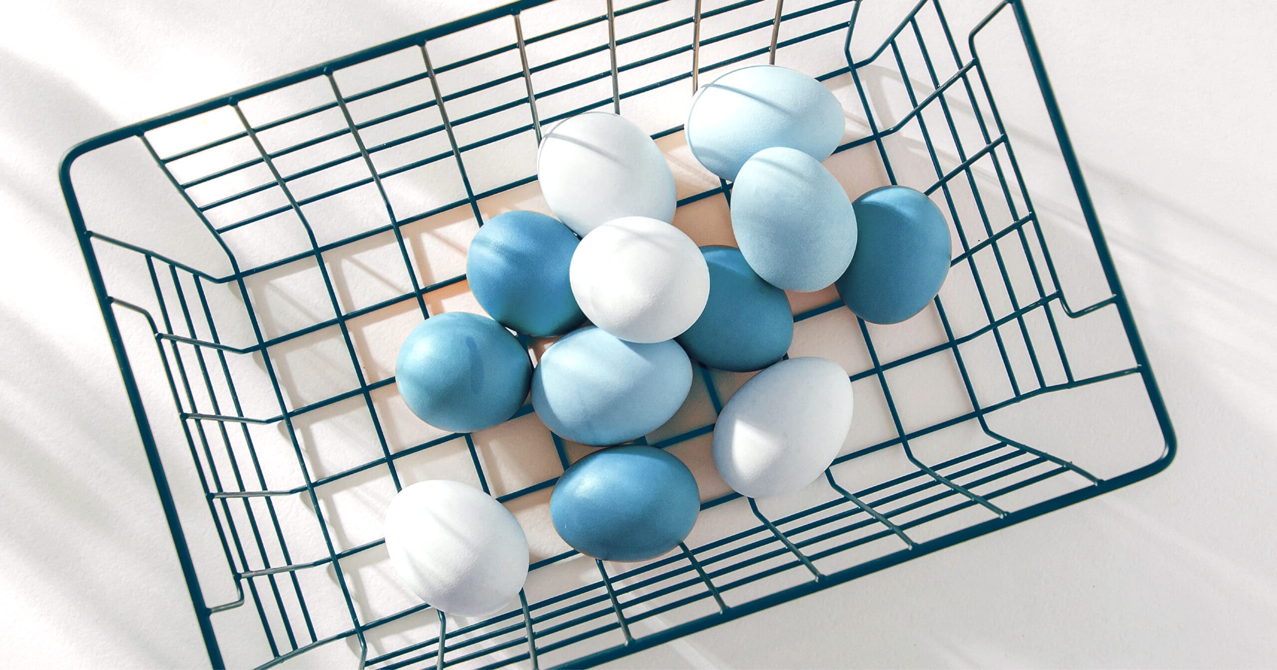 top view of blue-tinted eggs inside a wire basket on a whilte background